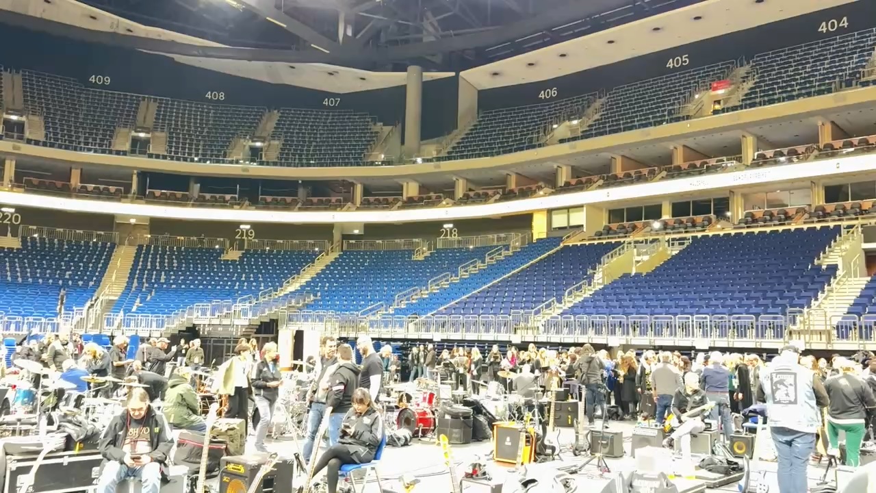 Photo of the interior of an arena, with several people setting up instruments